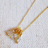 Gold-tone pendant necklace featuring a trio of stacked charms with sparkling crystal accents in a delicate layered design.