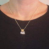 Gold-tone pendant necklace featuring a trio of stacked charms with sparkling crystal accents in a delicate layered design.