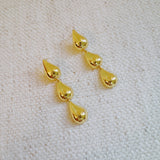 Gold-tone earrings featuring three cascading teardrop shapes in a tiered design, creating an elegant and fluid silhouette.