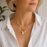 Woman wearing a gold butterfly necklace with a white shirt.