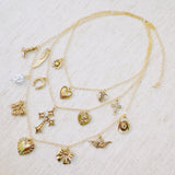 Multi-layered gold necklace featuring an eclectic mix of vintage-style charms including hearts, a cross, butterfly, bow, horseshoe, pearl, and more—creating a bold, expressive statement piece.