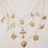 Multi-layered gold necklace featuring an eclectic mix of vintage-style charms including hearts, a cross, butterfly, bow, horseshoe, pearl, and more—creating a bold, expressive statement piece.
