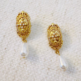 Gold oval stud earrings featuring a detailed cross design and dangling teardrop pearls—blending vintage charm with timeless elegance.