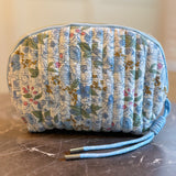 Quilted cosmetic case featuring a vintage-inspired floral print with soft padding and a structured shape, designed for storing makeup and small essentials.