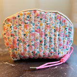 Quilted cosmetic case featuring a vintage-inspired floral print with soft padding and a structured shape, designed for storing makeup and small essentials.