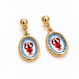 Pair of earrings with red lobster design on a blue background, gold accents.