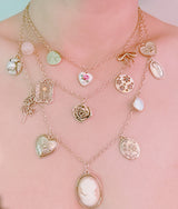 Multi-layered gold-tone necklace featuring an array of vintage-style charms including roses, cameos, hearts, and lockets—offering a romantic and nostalgic look perfect for statement styling.