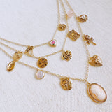 Multi-layered gold-tone necklace featuring an array of vintage-style charms including roses, cameos, hearts, and lockets—offering a romantic and nostalgic look perfect for statement styling.
