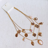 Multi-layered gold-tone necklace featuring an array of vintage-style charms including roses, cameos, hearts, and lockets—offering a romantic and nostalgic look perfect for statement styling.
