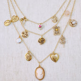 Multi-layered gold-tone necklace featuring an array of vintage-style charms including roses, cameos, hearts, and lockets—offering a romantic and nostalgic look perfect for statement styling.