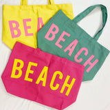 Three colorful tote bags with 'BEACH' text on a white background