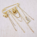 Gold-tone safety pin brooch featuring Western-themed charms including a horse, cowboy hat, boot, and layered chains—perfect for adding rustic flair to any outfit or bag.