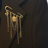 Gold-tone safety pin brooch featuring Western-themed charms including a horse, cowboy hat, boot, and layered chains—perfect for adding rustic flair to any outfit or bag.
