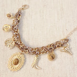 Scarf-wrapped bracelet featuring gold and sliver-tone Western-themed charms including a cowboy boot, sunburst, and lasso motifs