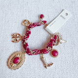 Scarf-wrapped bracelet featuring gold and sliver-tone Western-themed charms including a cowboy boot, sunburst, and lasso motifs