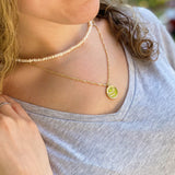 pearl necklace close to neck layered with constellation zodiac medallion pendant necklace on person