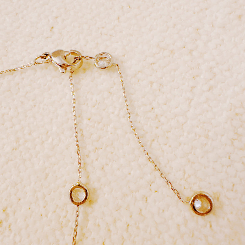 Delicate gold-tone necklace featuring twelve evenly spaced bezel-set sparkling stones along a fine chain, offering a dainty and radiant look