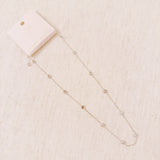 Delicate gold-tone necklace featuring twelve evenly spaced bezel-set sparkling stones along a fine chain, offering a dainty and radiant look