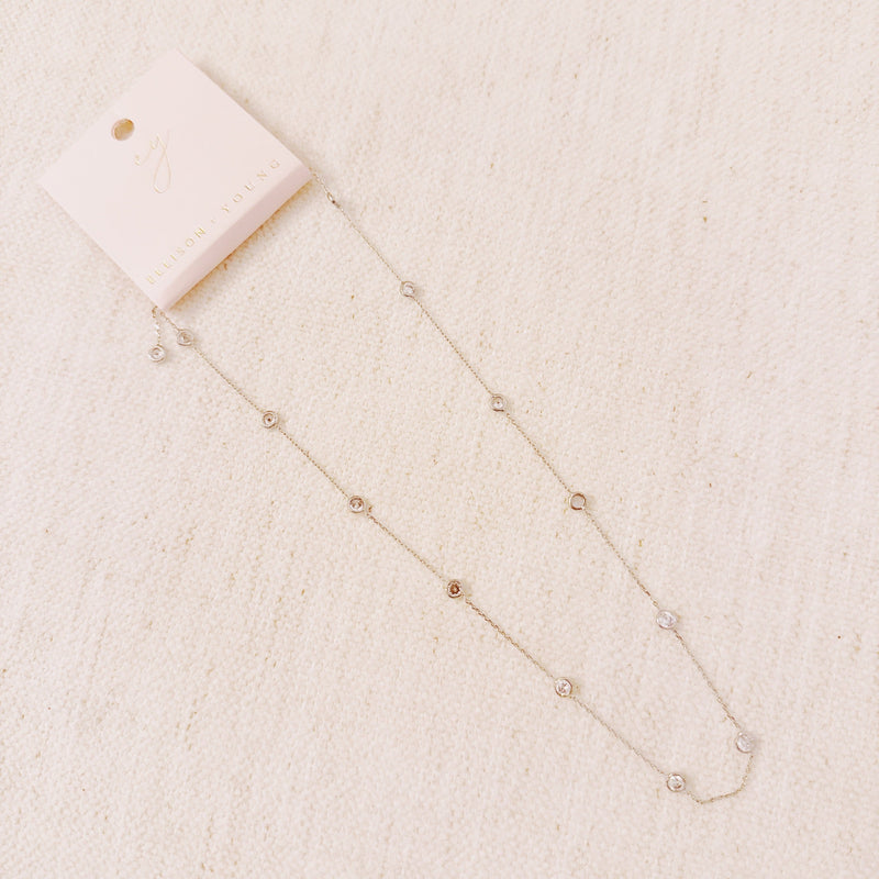 Delicate gold-tone necklace featuring twelve evenly spaced bezel-set sparkling stones along a fine chain, offering a dainty and radiant look