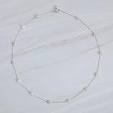 Delicate gold-tone necklace featuring twelve evenly spaced bezel-set sparkling stones along a fine chain, offering a dainty and radiant look