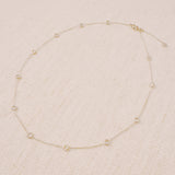 Delicate gold-tone necklace featuring twelve evenly spaced bezel-set sparkling stones along a fine chain, offering a dainty and radiant look