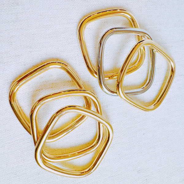 Two sets of square-shaped stacking bangles—one in solid gold-tone and one in a mixed gold and silver finish