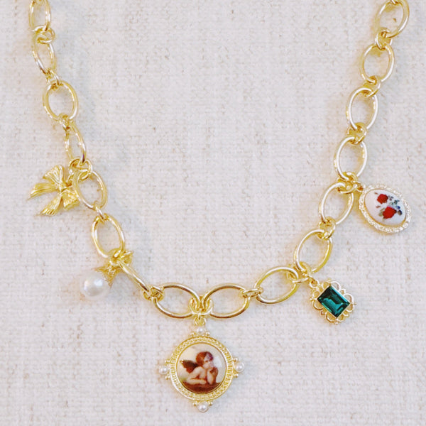  Chunky gold-link necklace featuring a mix of whimsical charms including an angel, rose, and gem accents—blending vintage elegance with romantic flair.