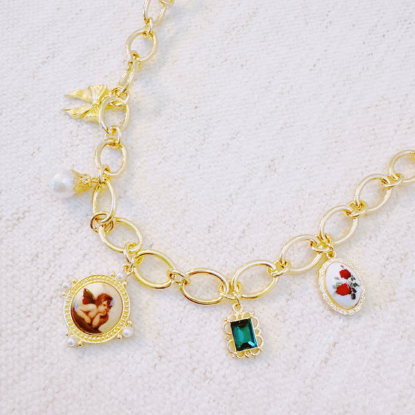  Chunky gold-link necklace featuring a mix of whimsical charms including an angel, rose, and gem accents—blending vintage elegance with romantic flair.