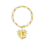 Gold bracelet with a heart-shaped charm featuring the letter 'E' on a white background