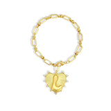 Gold chain bracelet with a heart-shaped charm and initial letter L over the heart charm on a white background