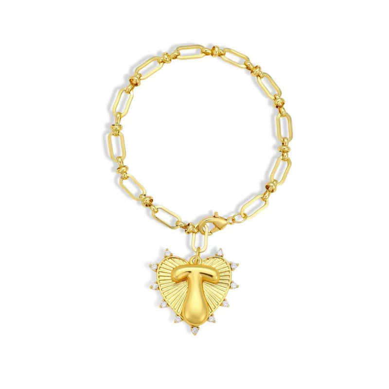 Gold chain bracelet with a heart-shaped charm and initial letter T over the heart charm on a white background