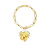 Gold chain bracelet with a heart-shaped charm and initial letter K over the heart charm on a white background
