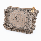 A beige bandana-patterned pouch with black paisley and floral motifs, featuring ruffled trim on all sides and a gold-tone zipper with a decorative gold charm.