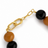 Bracelet with gold chain and black and brown beads on a white background