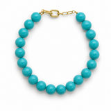 Turquoise beaded bracelet with gold chain on a white background