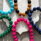 Colorful beaded bracelets on a white shell against a marble background