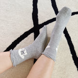 Set of two crew-length socks featuring charming embroidered Bichon Frise puppy design. Each pair showcases a soft color and is crafted from a stretchy & cozy material, perfect for everyday wear with a playful and cute flair.