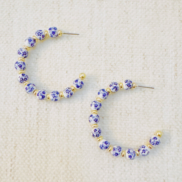 Stylish hoop earrings featuring delicate blue floral accents, offering a fresh and elegant look inspired by nature—ideal for springtime or everyday wear.