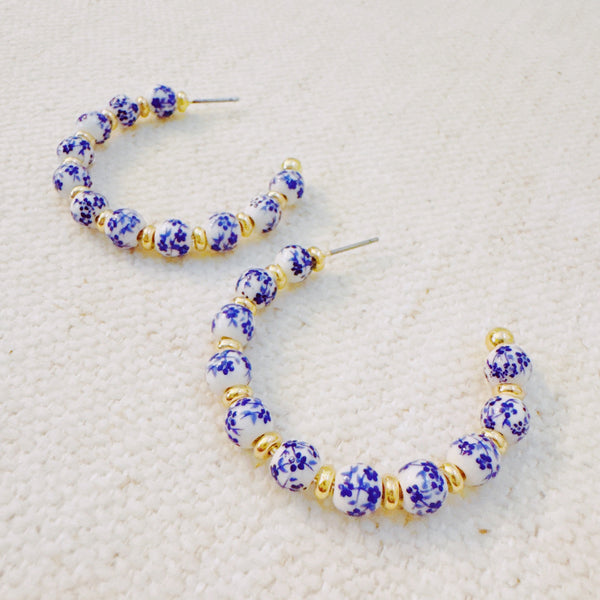 Stylish hoop earrings featuring delicate blue floral accents, offering a fresh and elegant look inspired by nature—ideal for springtime or everyday wear.