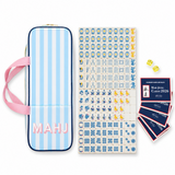 Ellison+Young Blue Porcelain Mahjong Tile Set with blue and white patterned crystal tiles and a light blue striped storage bag with pink handles.