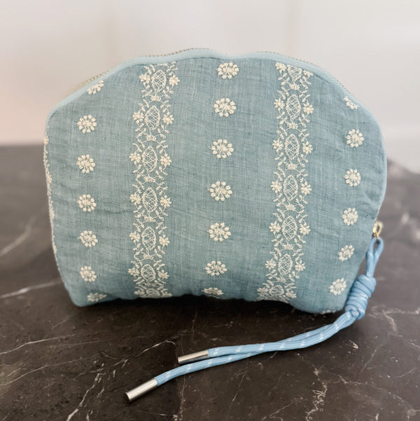Cosmetic case featuring a blue and white crochet-inspired pattern with a zip closure, perfect for storing beauty essentials with a cozy, crafted look.