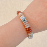 Stretch bracelet made of natural stone disc beads in soft blush, beige, and taupe tones arranged in a gradient pattern