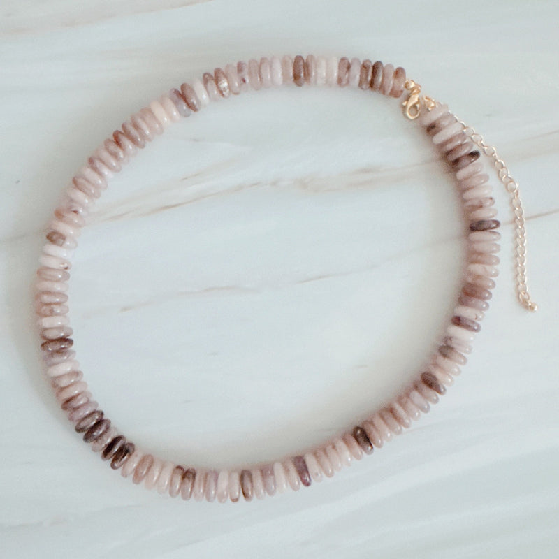 Beaded necklace made with natural stone disc beads in warm blush, beige, and soft brown tones arranged in a smooth, gradient pattern.