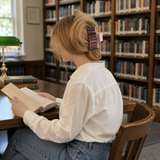Person sitting at a desk in a library reading a book.