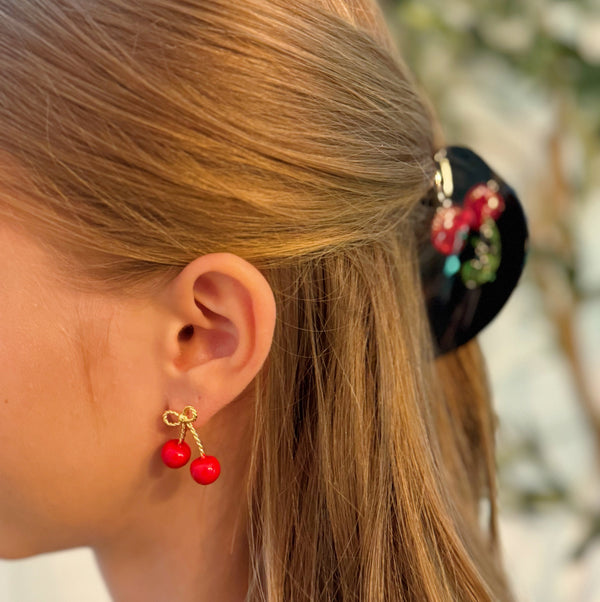Playful gold-tone earrings featuring a bow and cherry design, adding a whimsical and charming touch to your style.