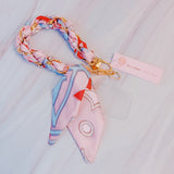 Stylish braided scarf lanyard featuring a gold-tone chain intertwined with patterned fabric, designed to securely attach to a phone while doubling as a chic fashion accessory.