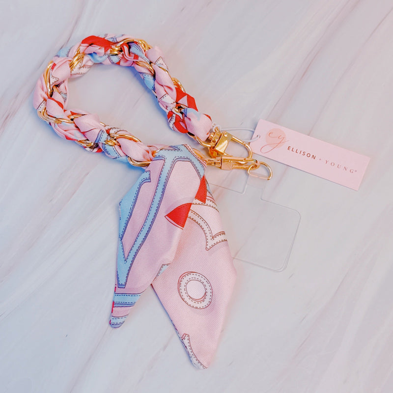 Stylish braided scarf lanyard featuring a gold-tone chain intertwined with patterned fabric, designed to securely attach to a phone while doubling as a chic fashion accessory.