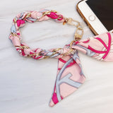 Stylish braided scarf lanyard featuring a gold-tone chain intertwined with patterned fabric, designed to securely attach to a phone while doubling as a chic fashion accessory.