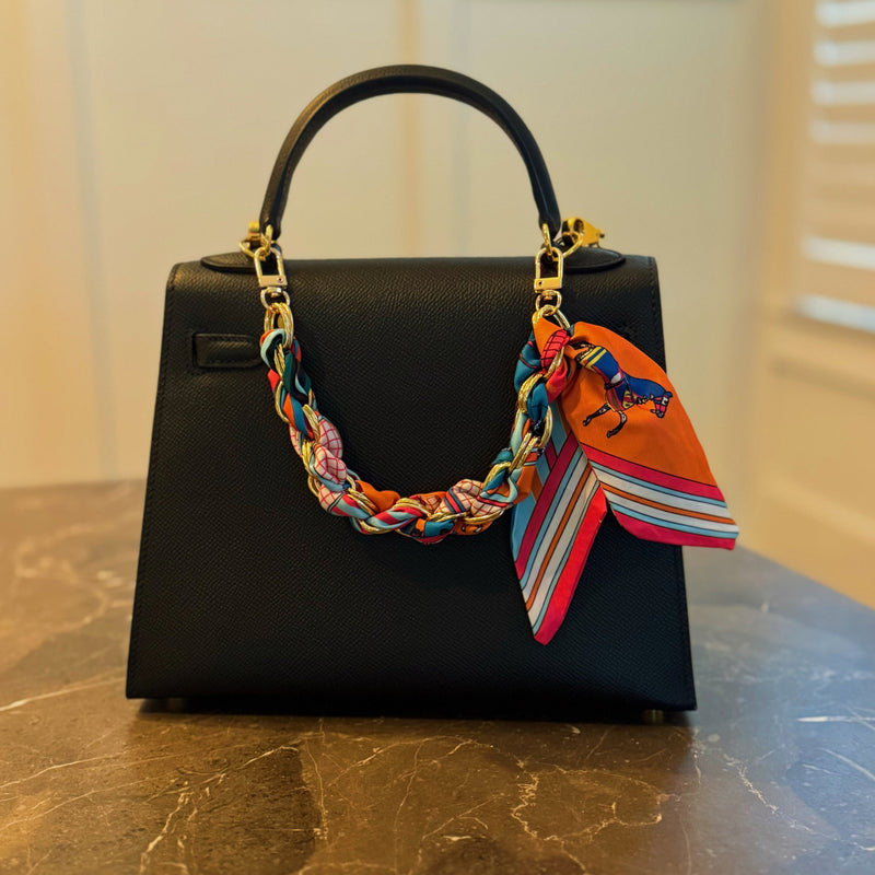 Stylish braided scarf lanyard featuring a gold-tone chain intertwined with patterned fabric, designed to securely attach to a phone while doubling as a chic fashion accessory.