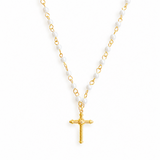 Necklace with gold cross pendant and white beaded chain on a white background